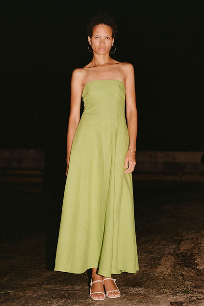 Woman wearing a strapless green dress standing against a dark background