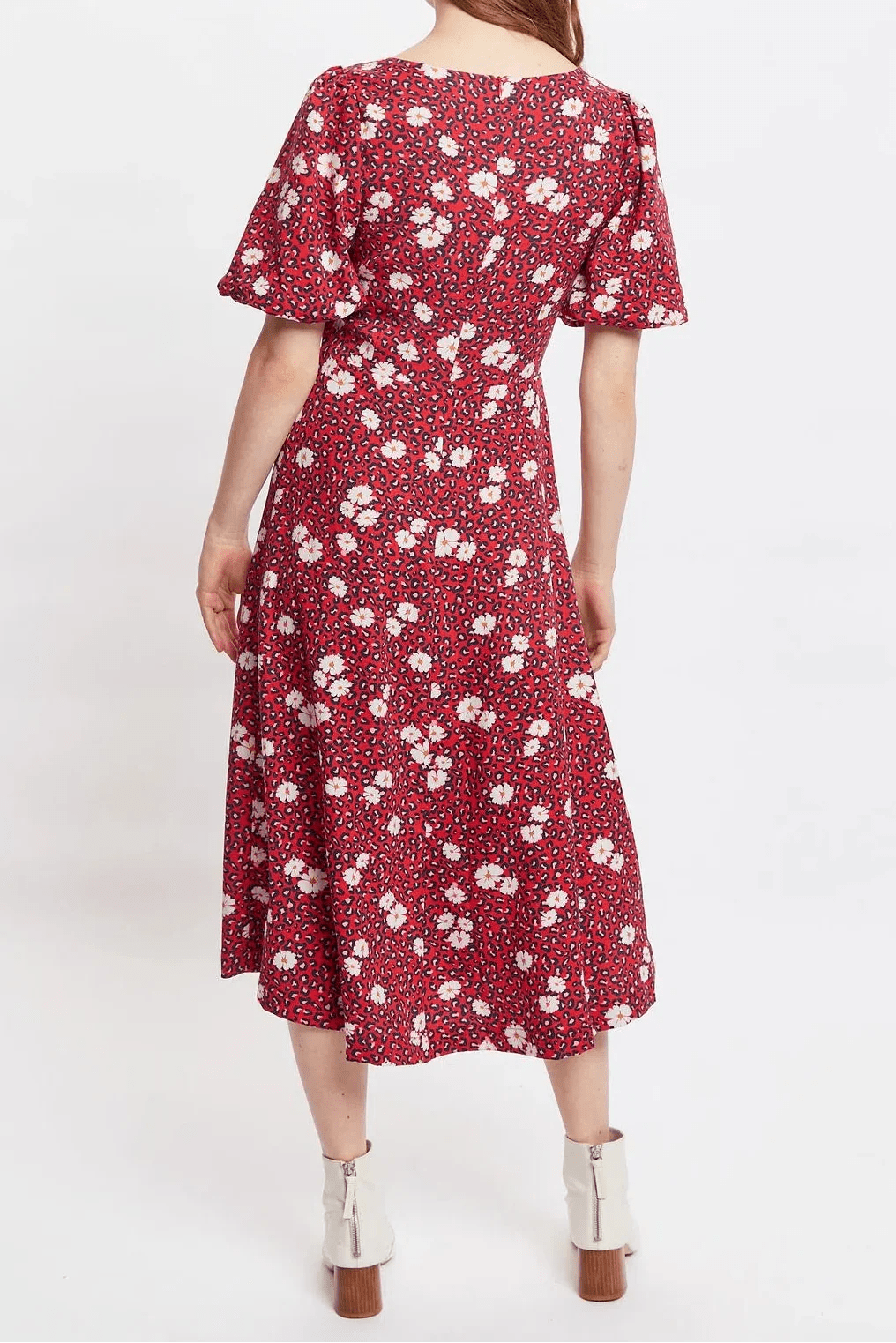 Woman in a red floral dress standing in studio.