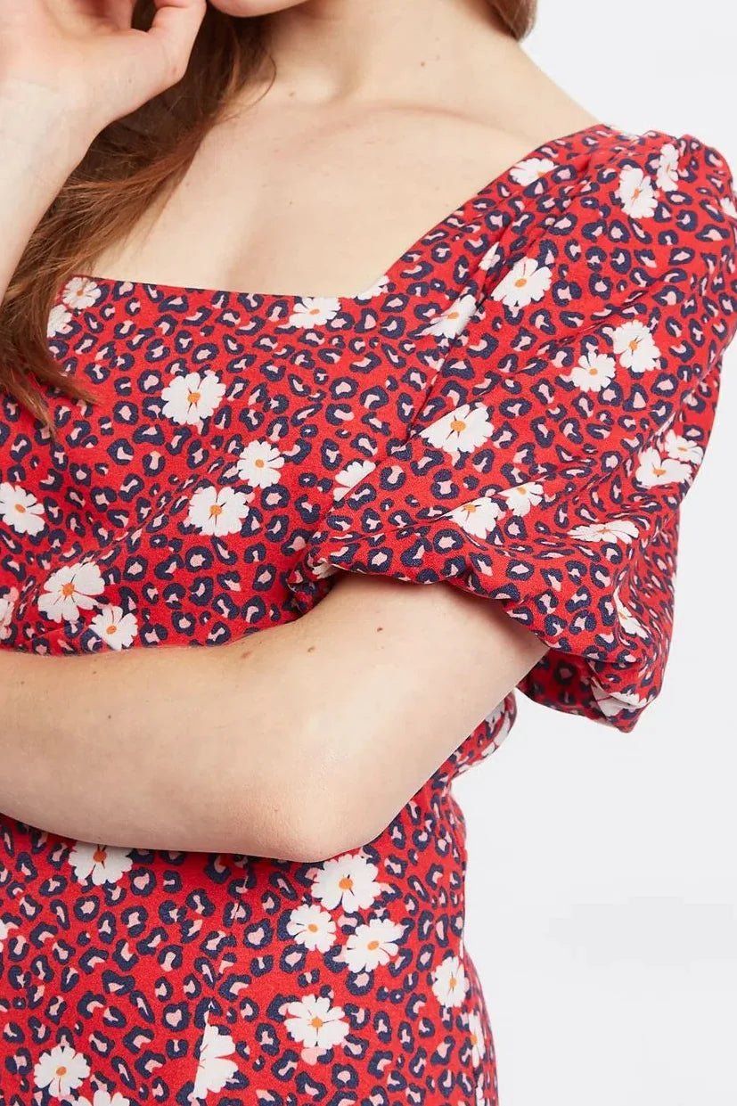 close up of Woman in a red floral dress standing in studio.