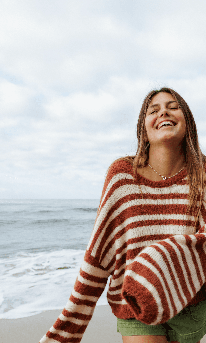 close up of Woman wearing a striped sweater and green shorts on a white background