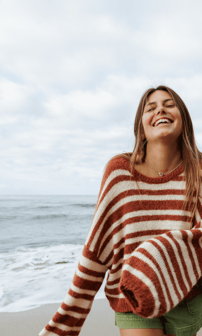 close up of Woman wearing a striped sweater and green shorts on a white background