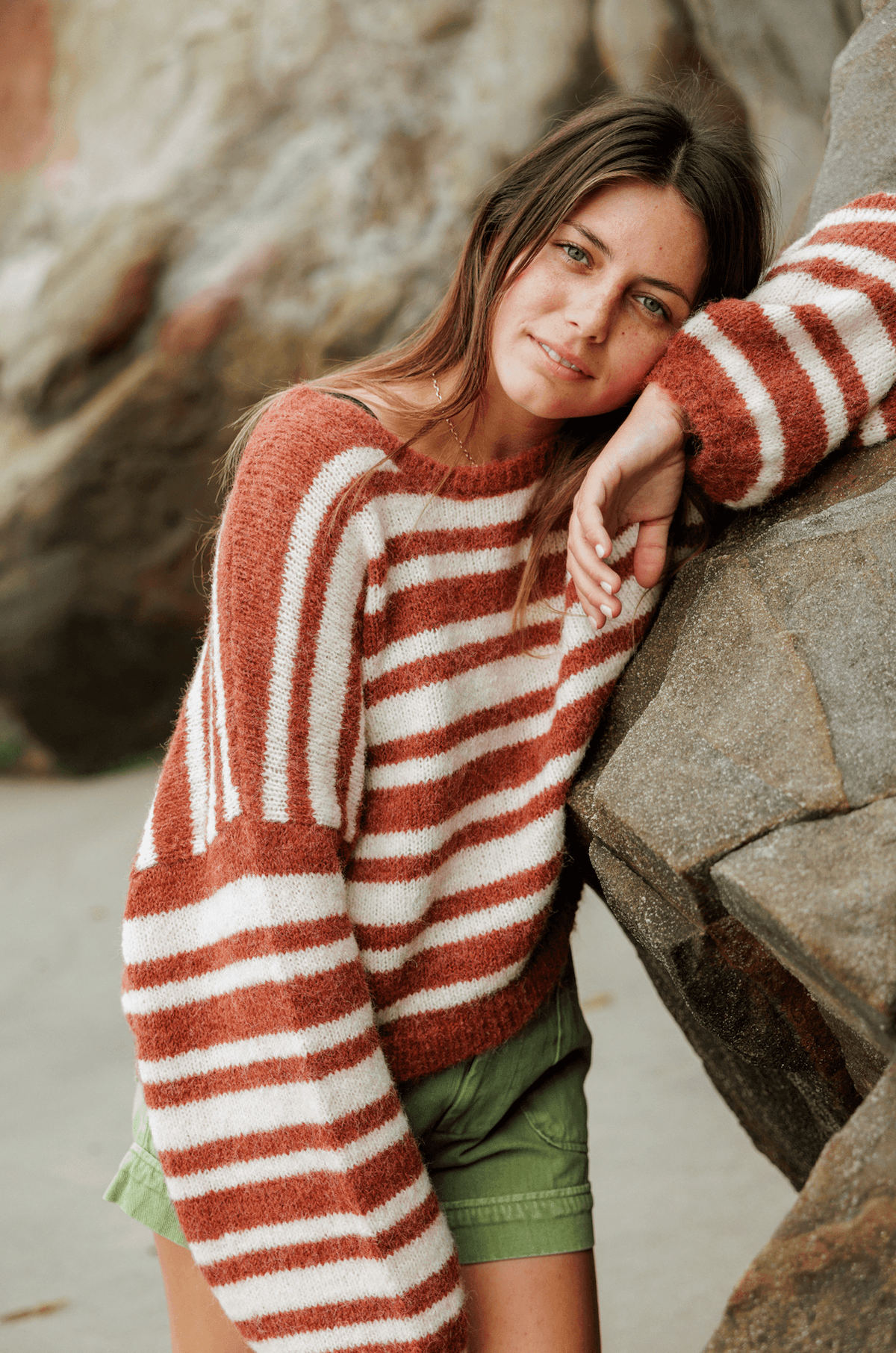 close up of Woman wearing a striped sweater and green shorts on a white background on the beach