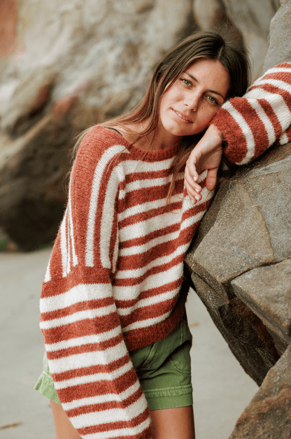 close up of Woman wearing a striped sweater and green shorts on a white background on the beach