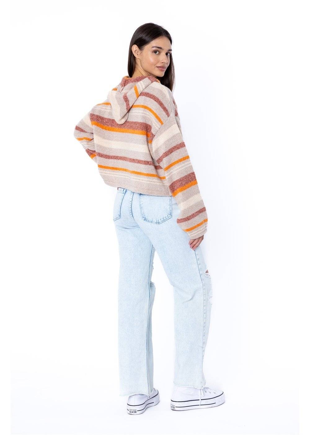 side of Woman wearing a striped sweater and light blue jeans on a white background