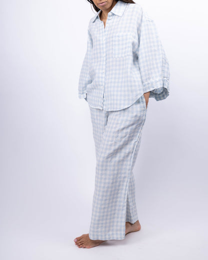 Person wearing a light blue checkered pajama set on a white background