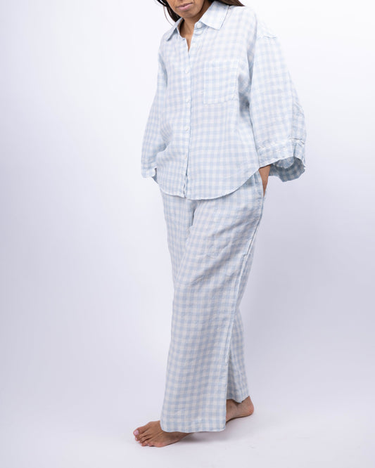 Person wearing a light blue checkered pajama set on a white background